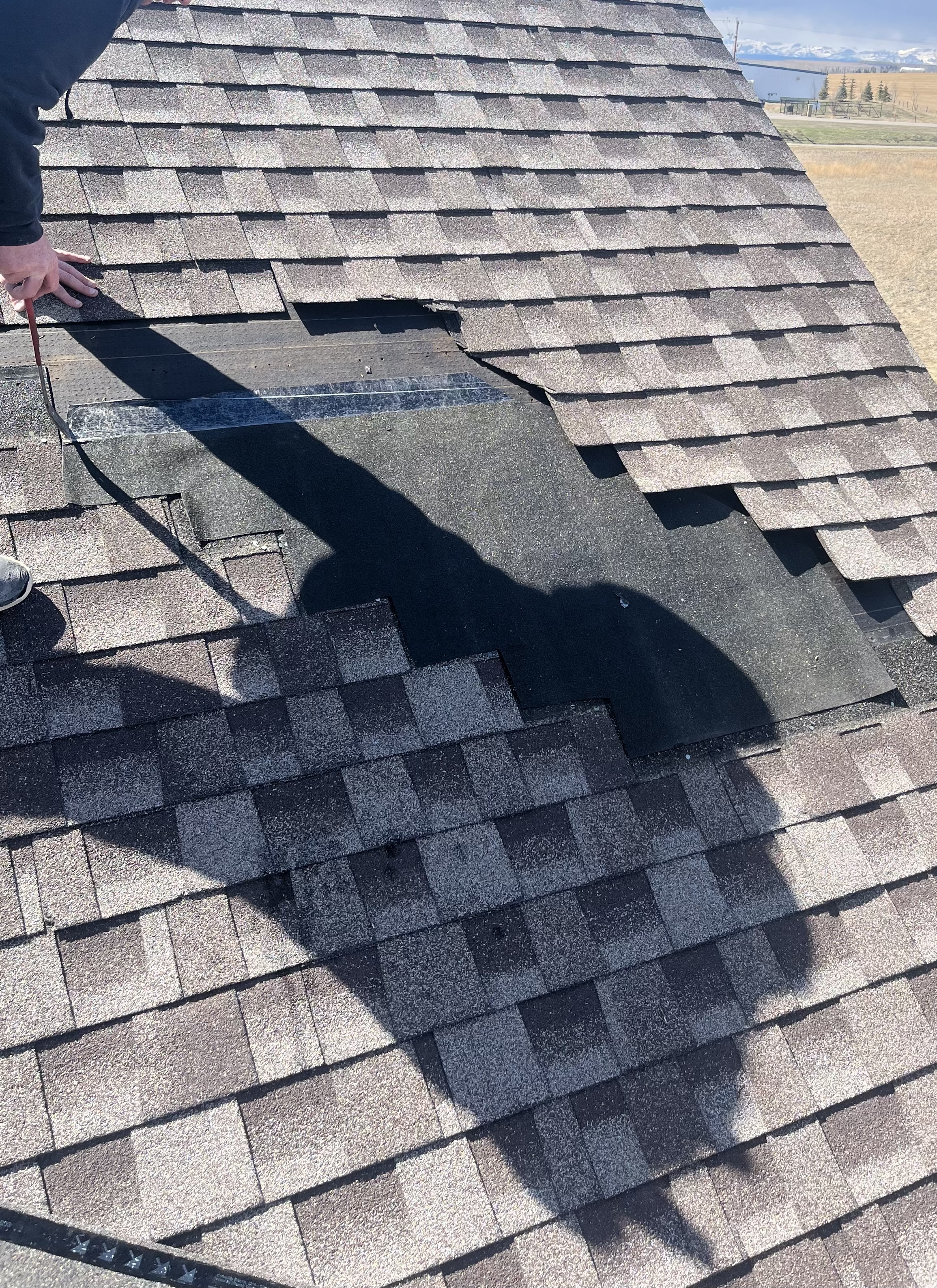 Wind-lifted shingles with exposed roof area and underlayment